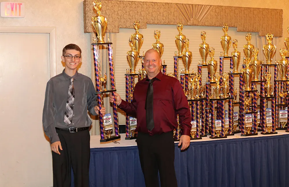 Two men holding large trophies at event