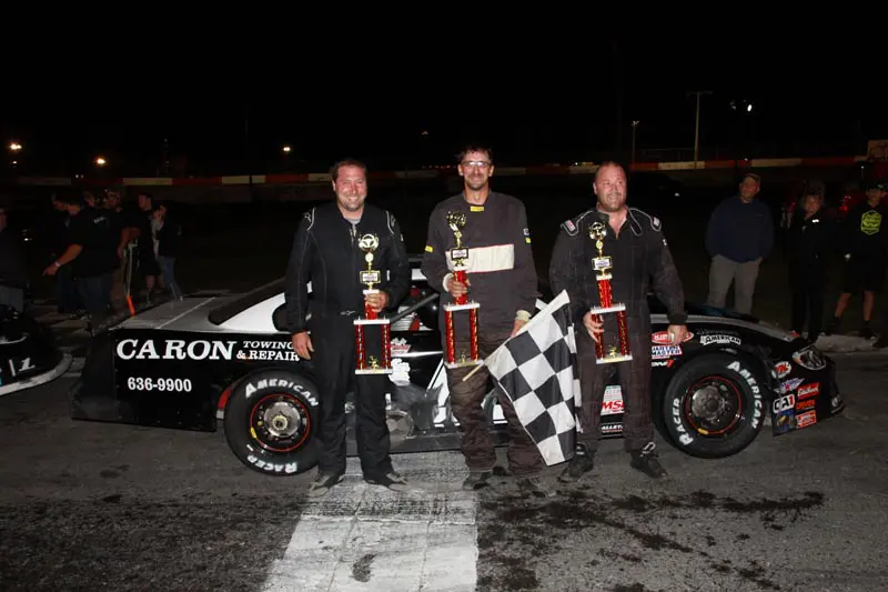 Three men with racing trophies and car