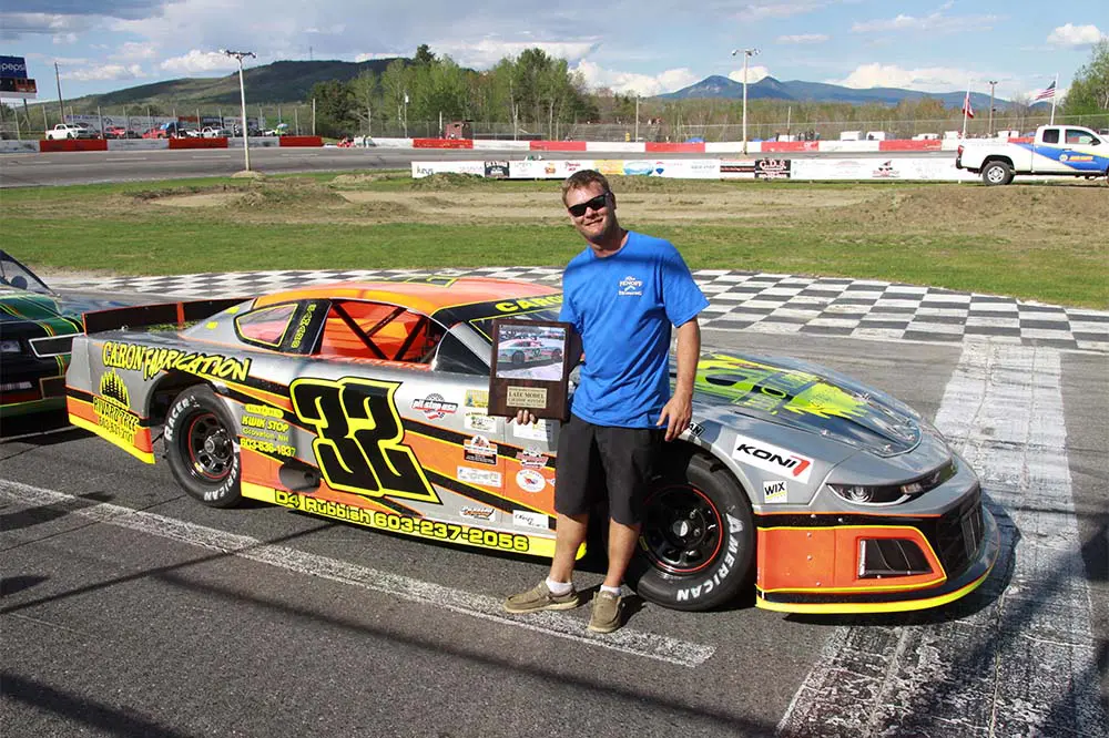 Man holding trophy beside race car