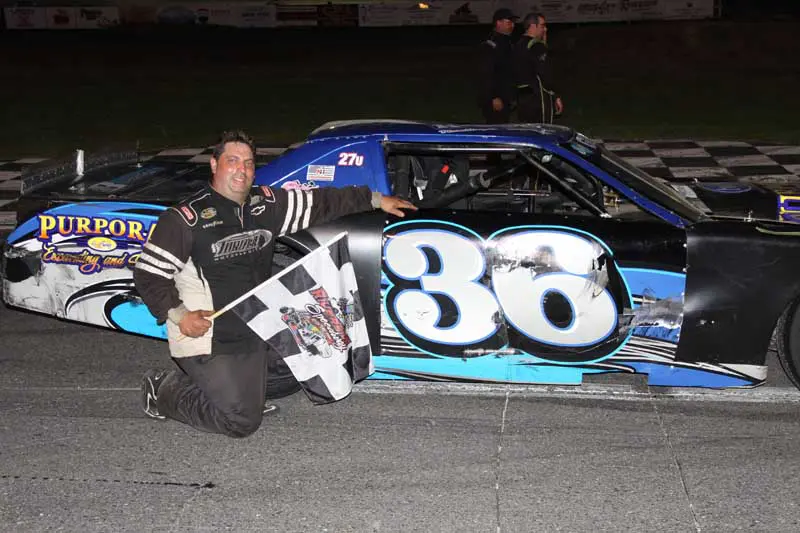Man kneeling beside blue race car